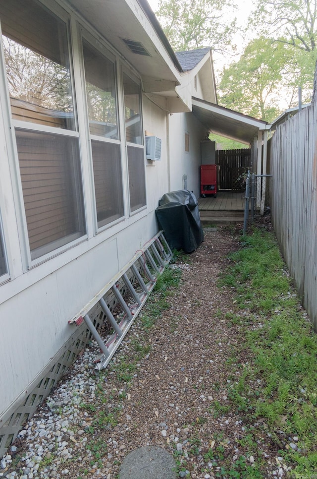 view of property exterior featuring cooling unit, a deck, and fence