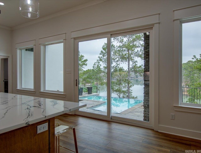 doorway featuring crown molding, baseboards, and wood finished floors