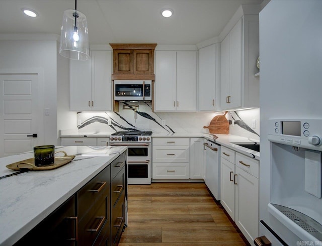 kitchen featuring white appliances, white cabinets, light wood finished floors, and pendant lighting