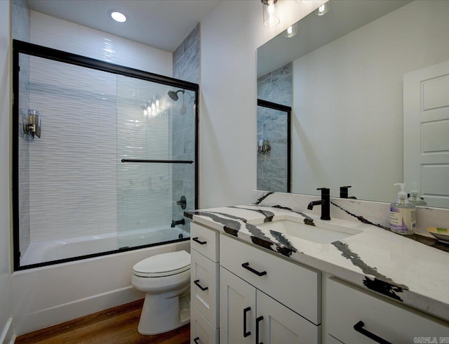 full bath with vanity, toilet, wood finished floors, and shower / bath combination with glass door