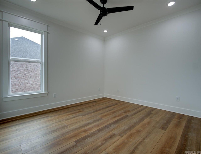 spare room with crown molding, wood finished floors, baseboards, and ceiling fan