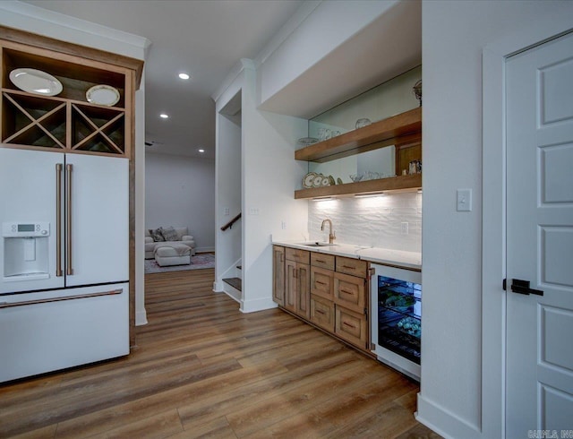 kitchen with light wood-type flooring, beverage cooler, a sink, backsplash, and white refrigerator with ice dispenser