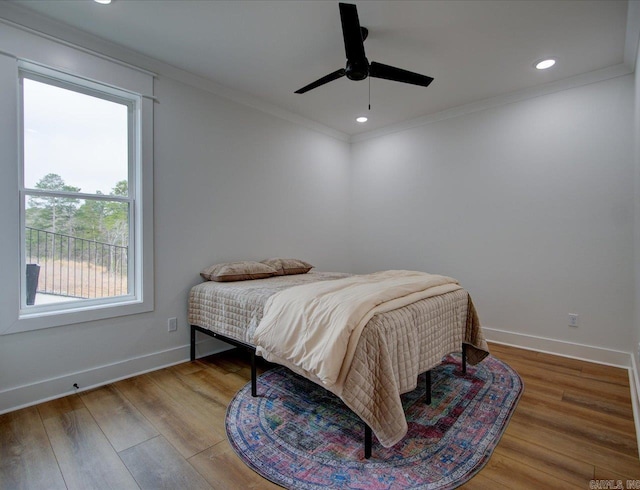 bedroom featuring recessed lighting, wood finished floors, baseboards, and ornamental molding