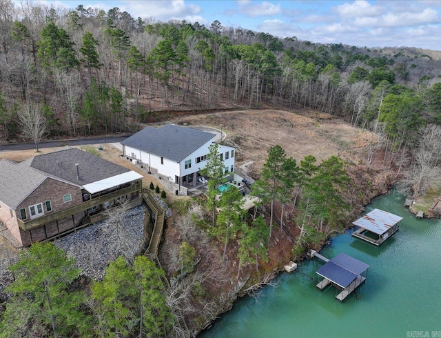 birds eye view of property featuring a forest view and a water view