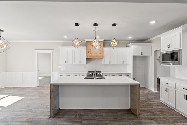 kitchen featuring stainless steel appliances, a kitchen island with sink, dark wood finished floors, and light countertops