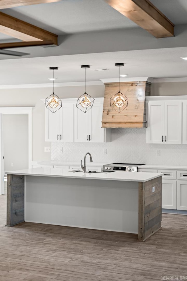 kitchen featuring a kitchen island with sink, beam ceiling, wood finished floors, and white cabinetry