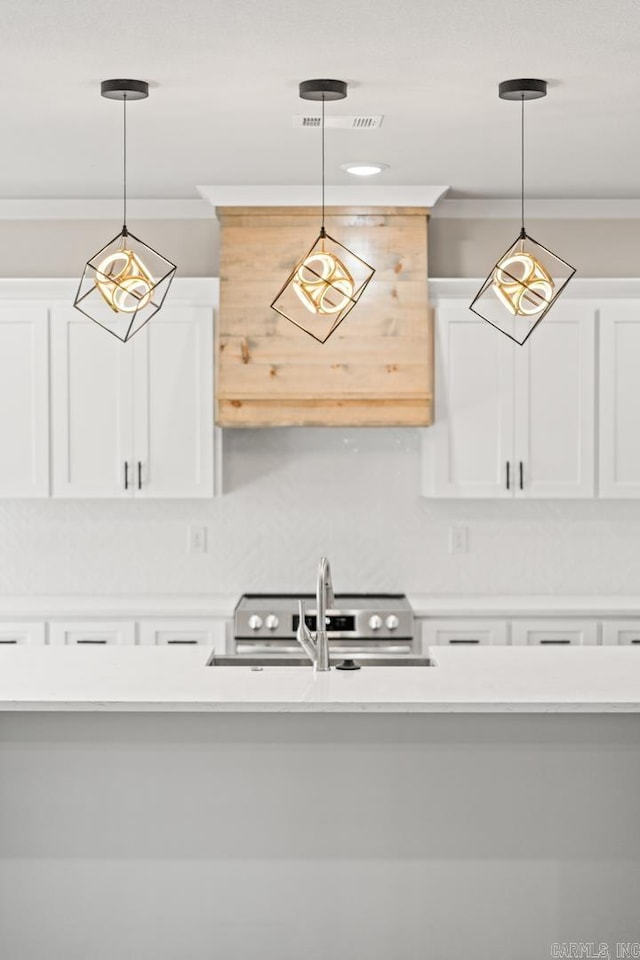 kitchen featuring a sink, pendant lighting, crown molding, and light countertops