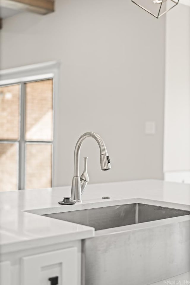 kitchen with white cabinetry, light countertops, and a sink