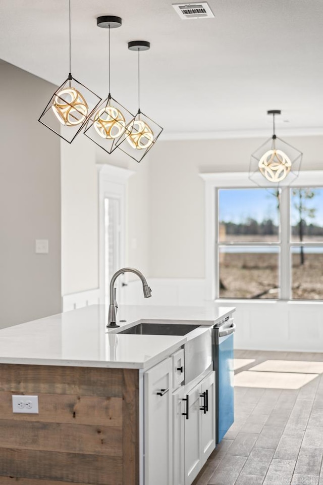 kitchen featuring a kitchen island with sink, visible vents, decorative light fixtures, white cabinets, and stainless steel dishwasher