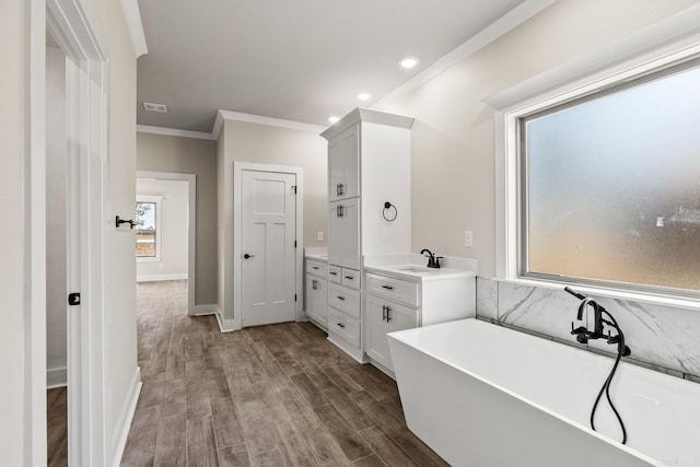 full bathroom featuring visible vents, crown molding, wood finished floors, a freestanding tub, and vanity