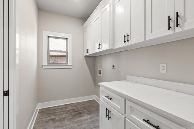 clothes washing area with baseboards, hookup for an electric dryer, dark wood finished floors, cabinet space, and washer hookup