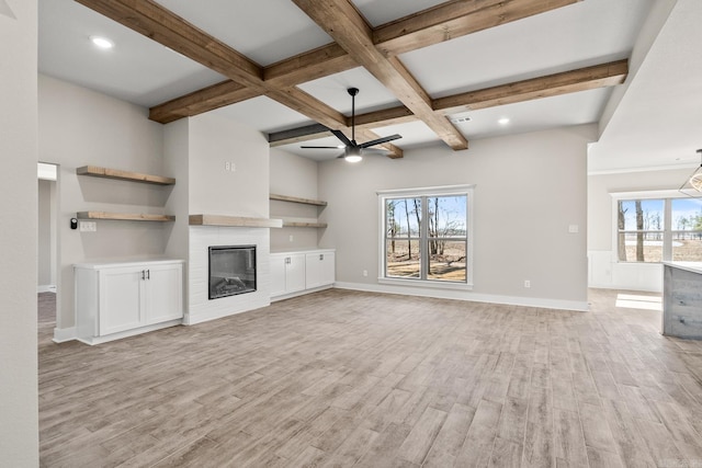 unfurnished living room featuring a glass covered fireplace, light wood-style flooring, beam ceiling, and ceiling fan