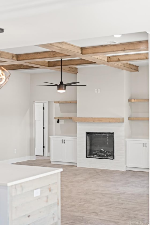 unfurnished living room featuring a glass covered fireplace, beamed ceiling, and light wood finished floors