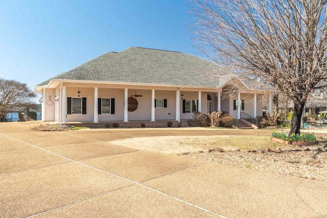 view of front of house with stucco siding, a porch, a shingled roof, and a ceiling fan