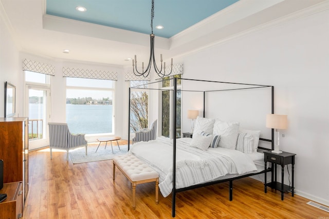 bedroom featuring a raised ceiling, crown molding, visible vents, and light wood-type flooring