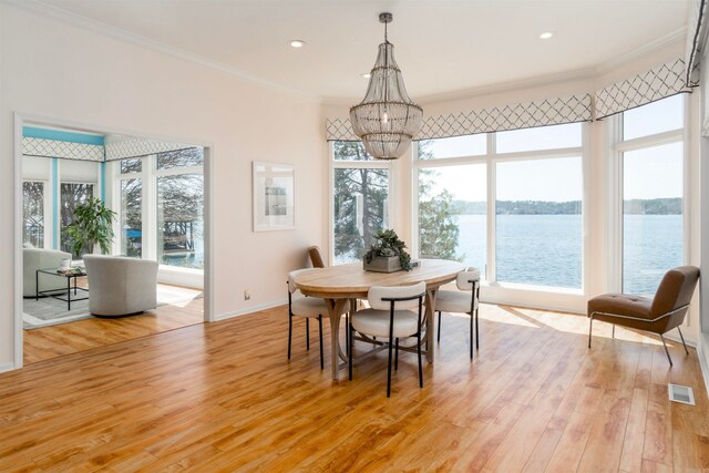 dining area with a notable chandelier, visible vents, light wood-type flooring, and ornamental molding