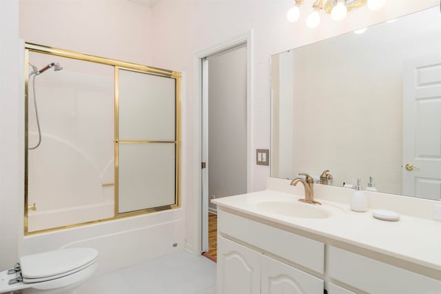 bathroom with vanity, toilet, and shower / bath combination with glass door