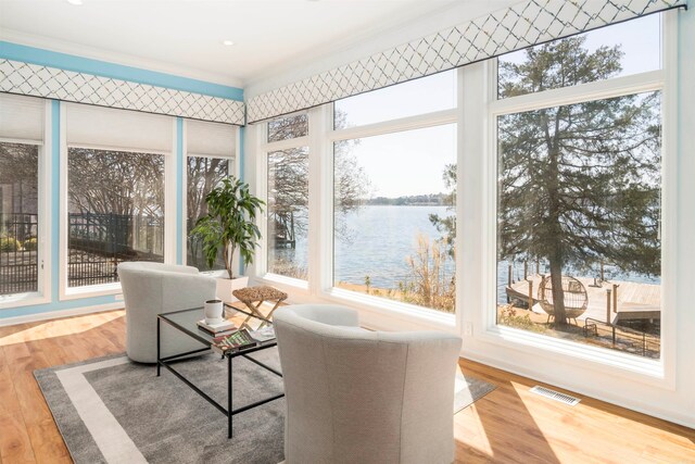 sunroom featuring visible vents and a water view