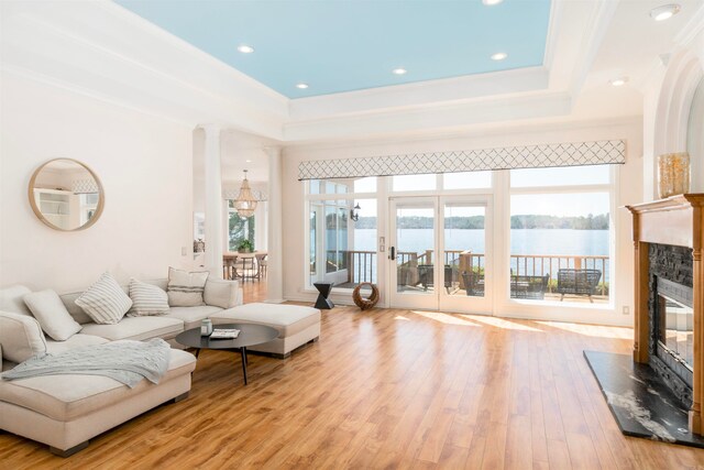 living room with a glass covered fireplace, ornamental molding, wood finished floors, and a water view