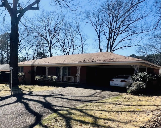 view of front facade featuring an attached carport, a porch, and driveway