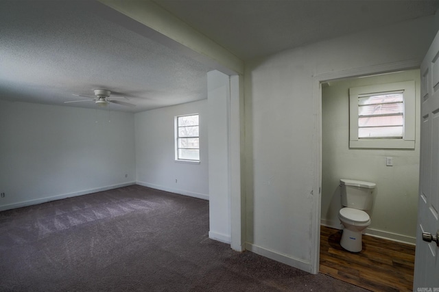 interior space with baseboards, a textured ceiling, a ceiling fan, and dark colored carpet