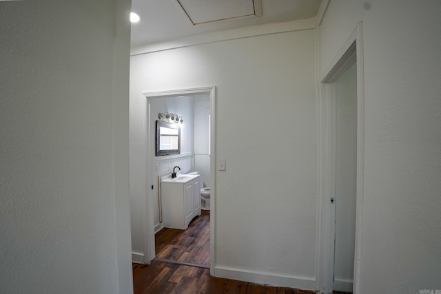 hall featuring dark wood finished floors, baseboards, and a sink