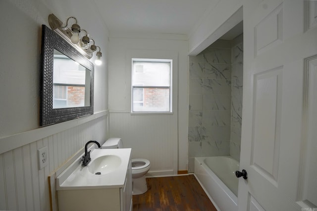 full bath with vanity, wood finished floors, a wainscoted wall, shower / bath combination, and toilet