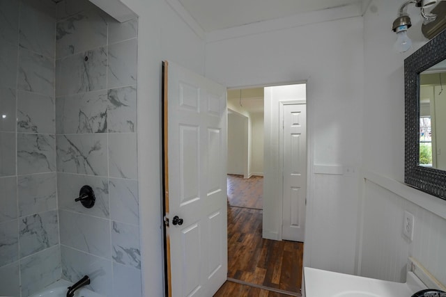 full bath with a wainscoted wall, wood finished floors, washtub / shower combination, and ornamental molding