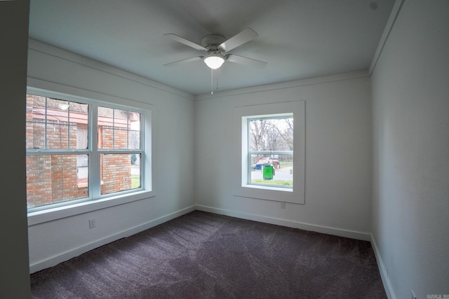 spare room featuring baseboards, crown molding, a ceiling fan, and dark colored carpet