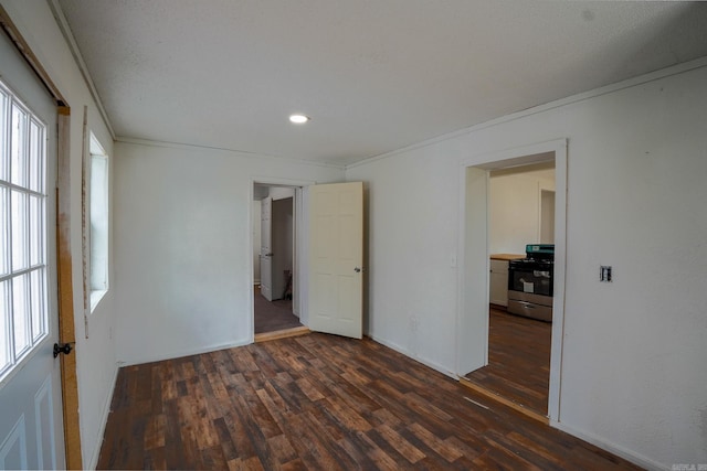 empty room with crown molding, dark wood-style floors, and baseboards