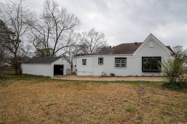 rear view of house featuring a garage, a lawn, an outdoor structure, crawl space, and brick siding