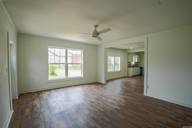 unfurnished living room with dark wood finished floors, a ceiling fan, and baseboards