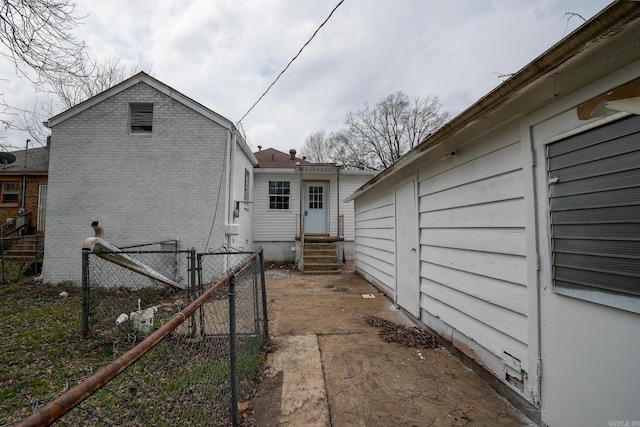 view of property exterior with a gate, fence, brick siding, and entry steps