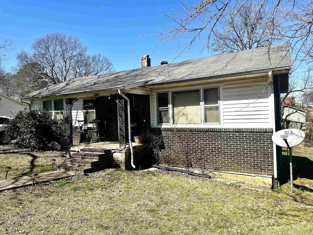 view of front of house with a front yard, brick siding, and a chimney