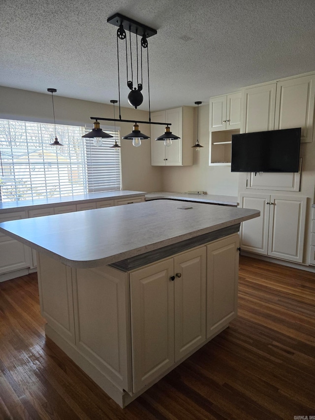 kitchen featuring dark wood-style floors, white cabinets, pendant lighting, and a kitchen island