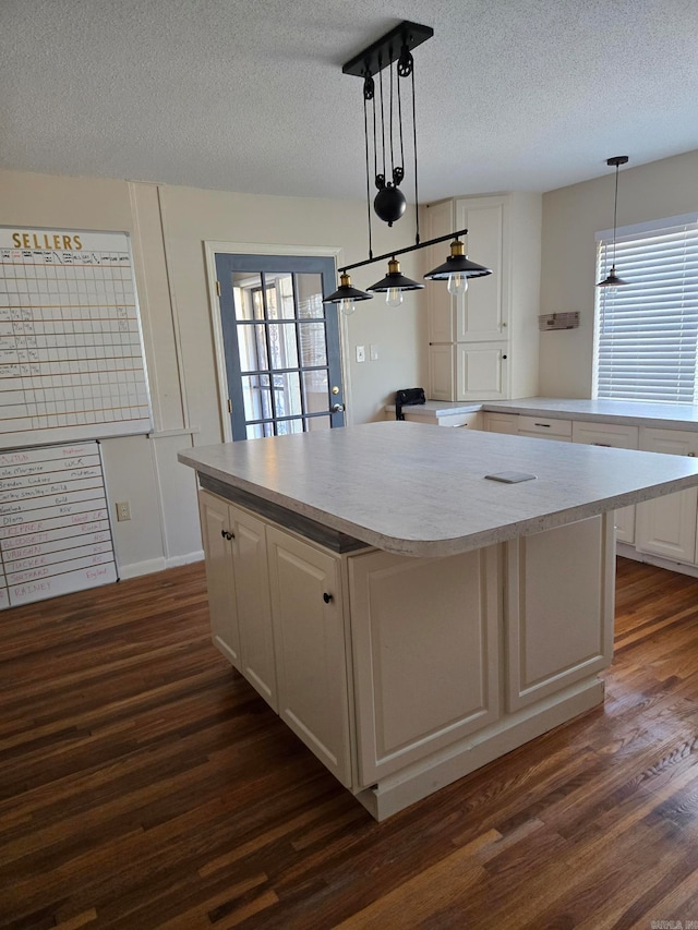 kitchen with plenty of natural light, dark wood finished floors, a center island, and white cabinetry