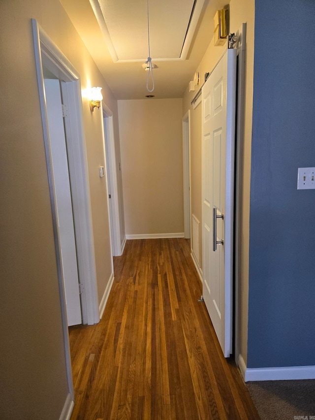 corridor featuring attic access, baseboards, and wood finished floors