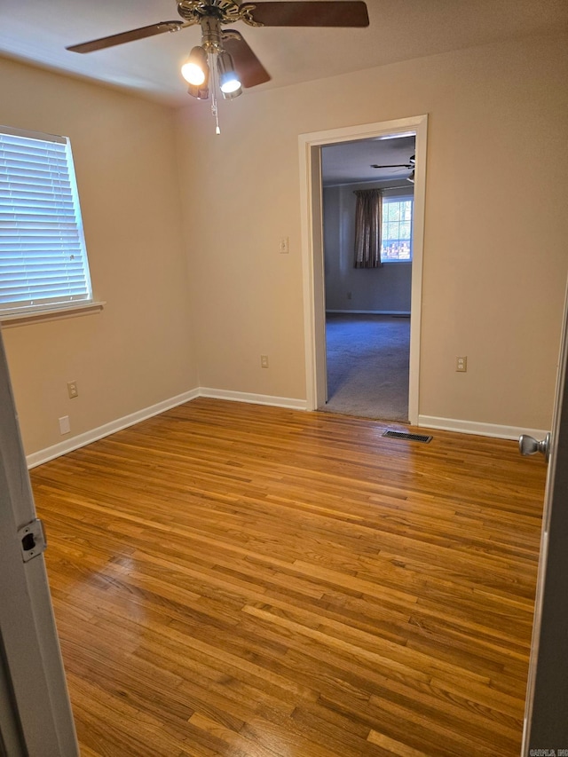 empty room featuring visible vents, baseboards, a ceiling fan, and wood finished floors