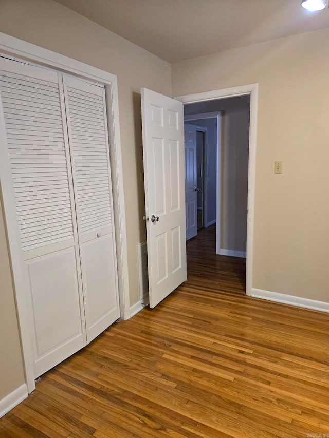 unfurnished bedroom with a closet, baseboards, and wood finished floors