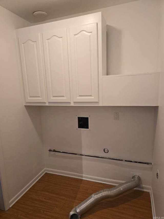 washroom with cabinet space, gas dryer hookup, baseboards, and wood finished floors