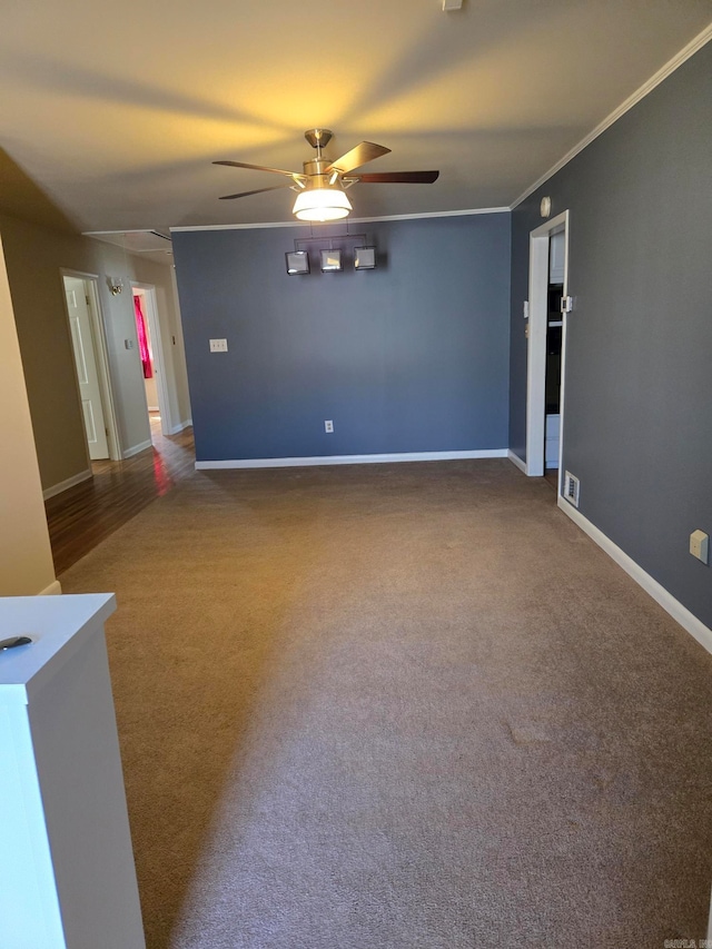 carpeted spare room with crown molding, a ceiling fan, baseboards, and visible vents