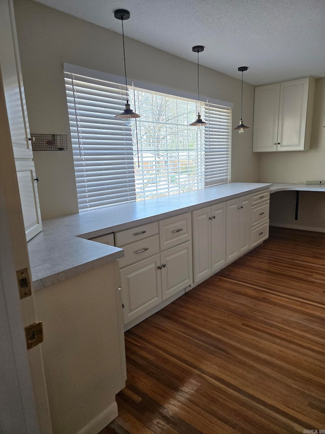 kitchen featuring pendant lighting, dark wood finished floors, light countertops, and white cabinetry