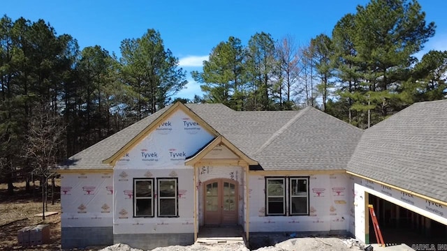 property under construction featuring french doors, a garage, and roof with shingles