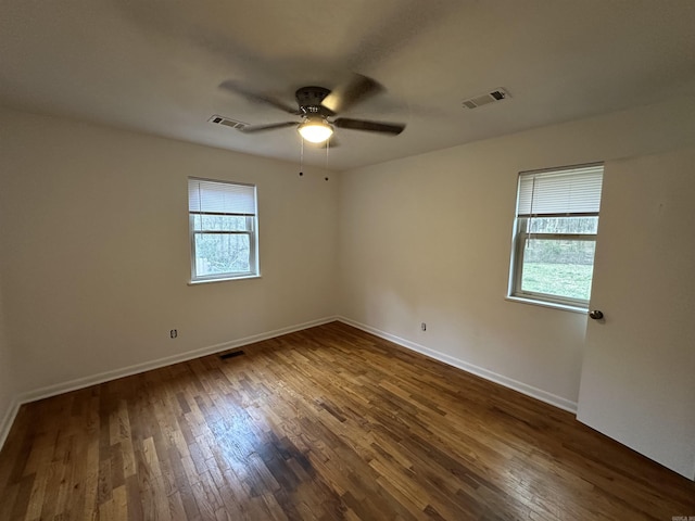 empty room with visible vents, dark wood-style floors, and ceiling fan