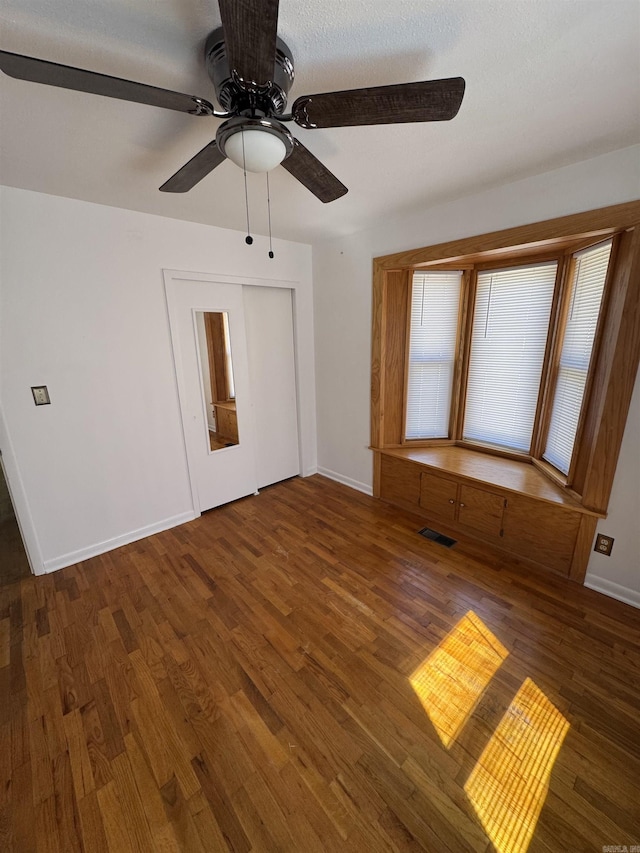 empty room featuring visible vents, baseboards, ceiling fan, and wood finished floors