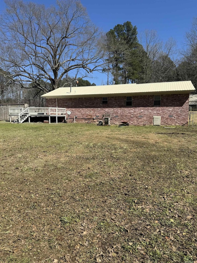 back of house with crawl space, a wooden deck, a lawn, and metal roof