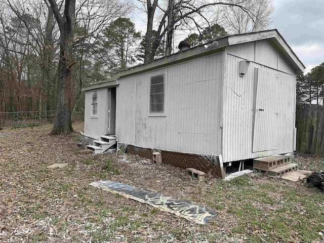 view of outbuilding featuring entry steps, an outdoor structure, and fence