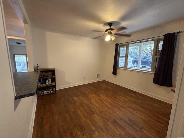 empty room with ceiling fan, visible vents, baseboards, and dark wood-style floors