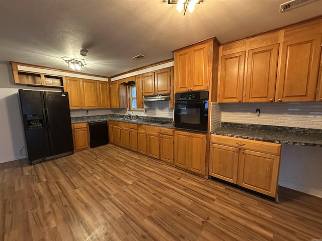 kitchen featuring visible vents, brown cabinets, black appliances, and wood finished floors