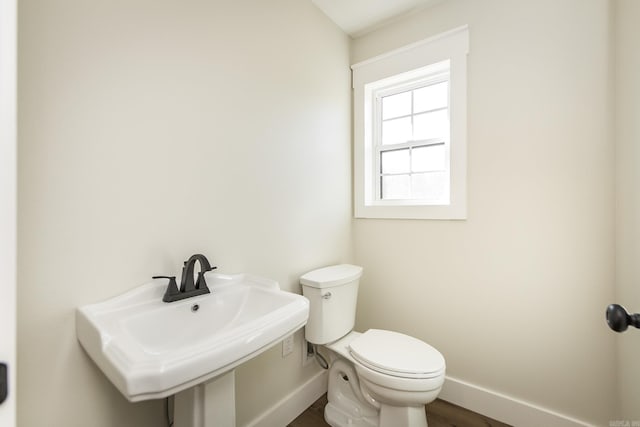 bathroom with toilet, baseboards, and a sink